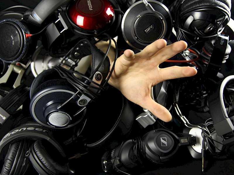 Pile of Hi-Fi headphones with hand reaching out from under them.