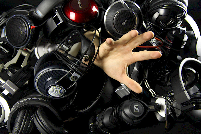 Pile of Hi-Fi headphones with hand reaching out from under them.